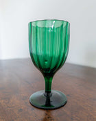 Green glass goblet on a wooden surface with a white background
