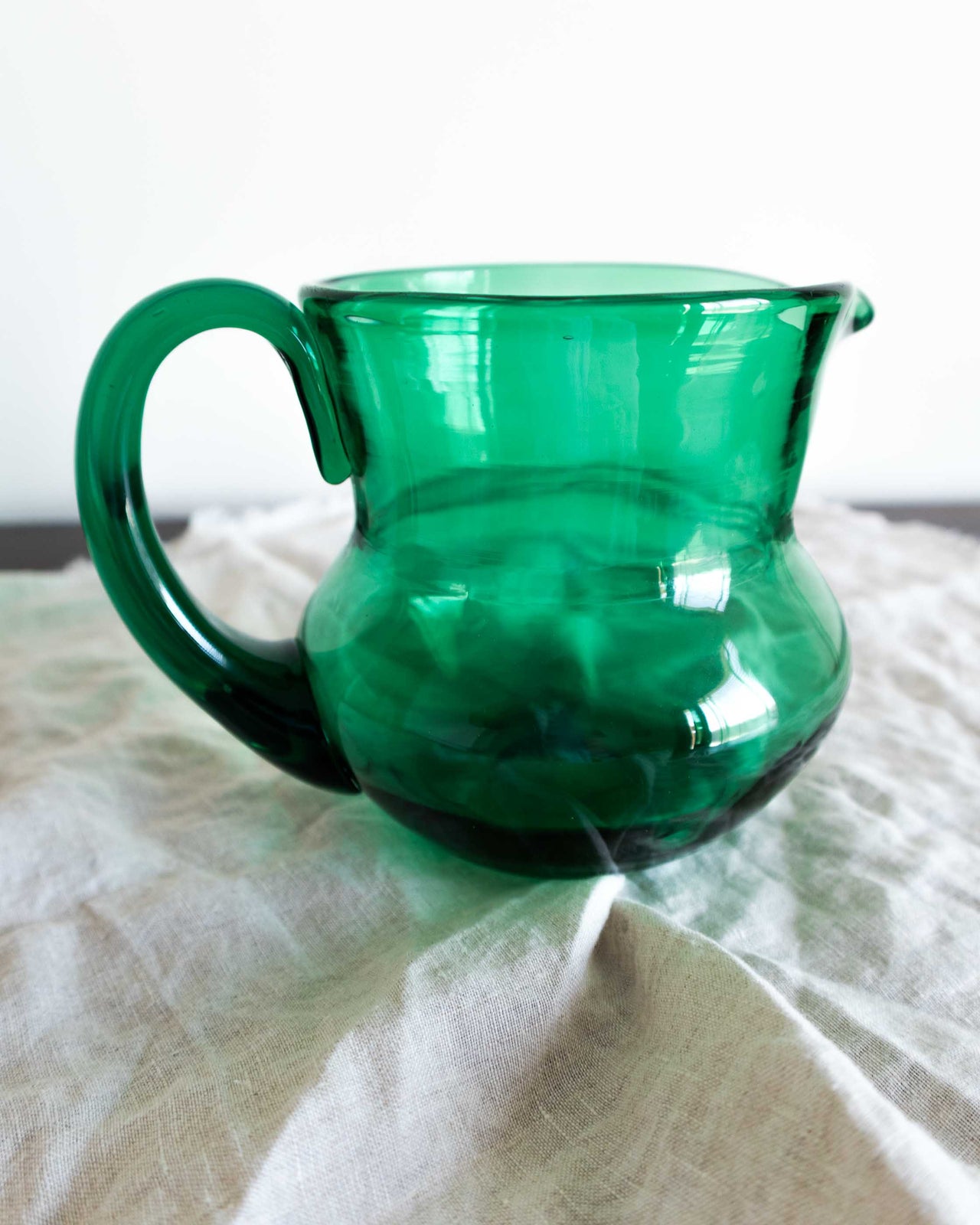 Green glass pitcher on a white surface