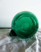 Green glass jug on a white fabric surface