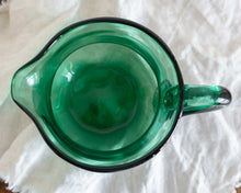 Green glass pitcher on a white fabric background