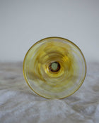 Yellow glass object on a textured surface with a neutral background