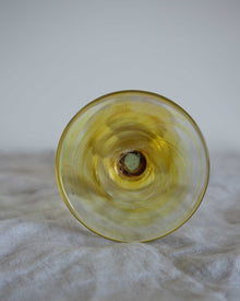 Yellow glass object on a textured surface with a neutral background