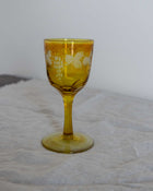 Yellow glass goblet with floral design on a textured surface