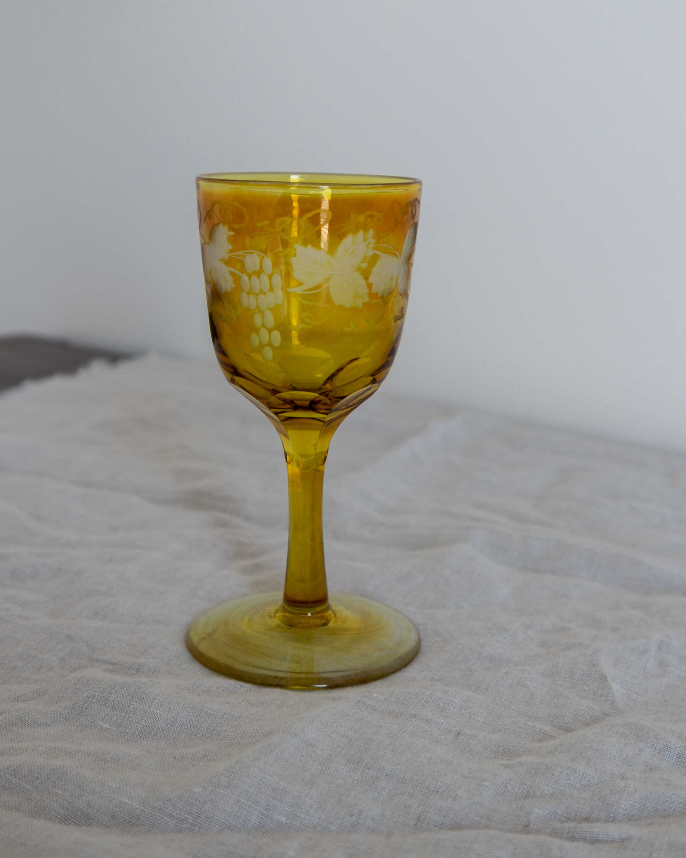 Yellow glass goblet with floral design on a textured surface