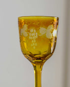 Yellow glass with floral and vine design on a plain background
