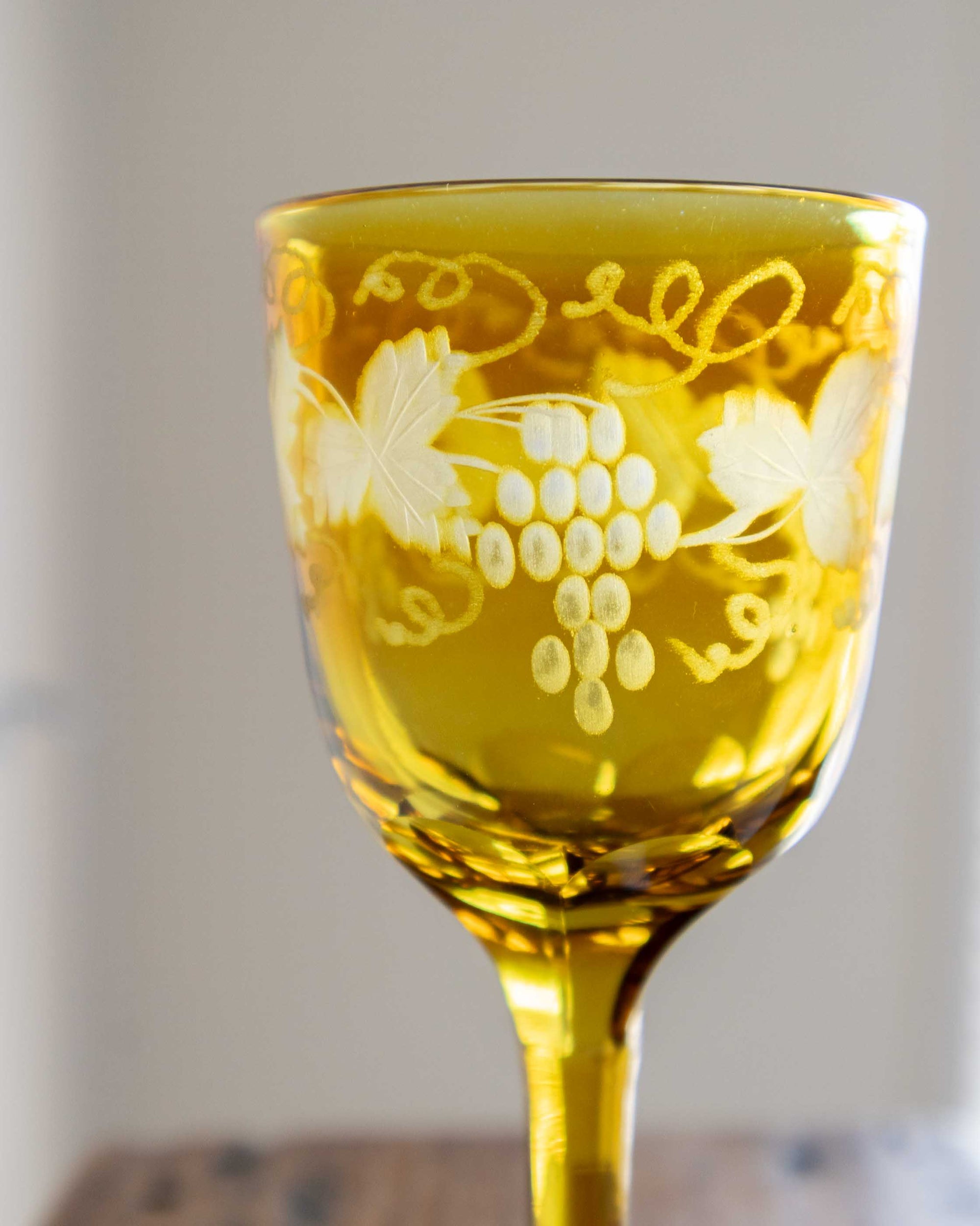 Yellow glass with floral etching on a blurred background