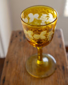 Decorative amber glass with floral patterns on a wooden surface