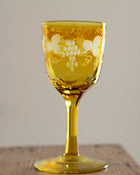 Yellow glass with floral patterns on a wooden surface