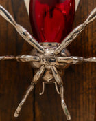 Close-up of a red glass object with silver  legs on a wooden background