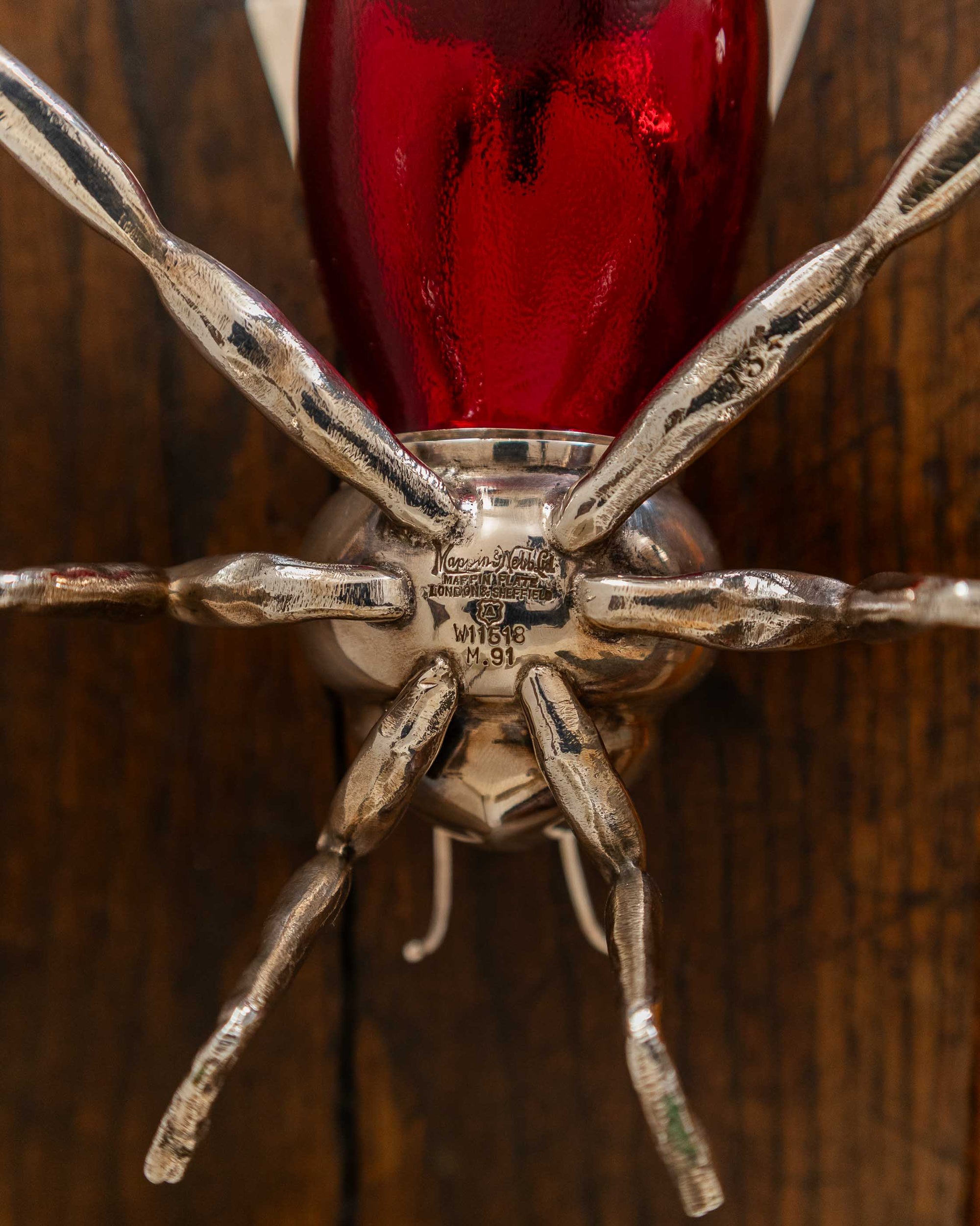 Close-up of a red glass object with silver  legs on a wooden background