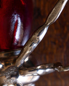 Decorative bee honey pot with a red glass base and metal legs on a wooden surface