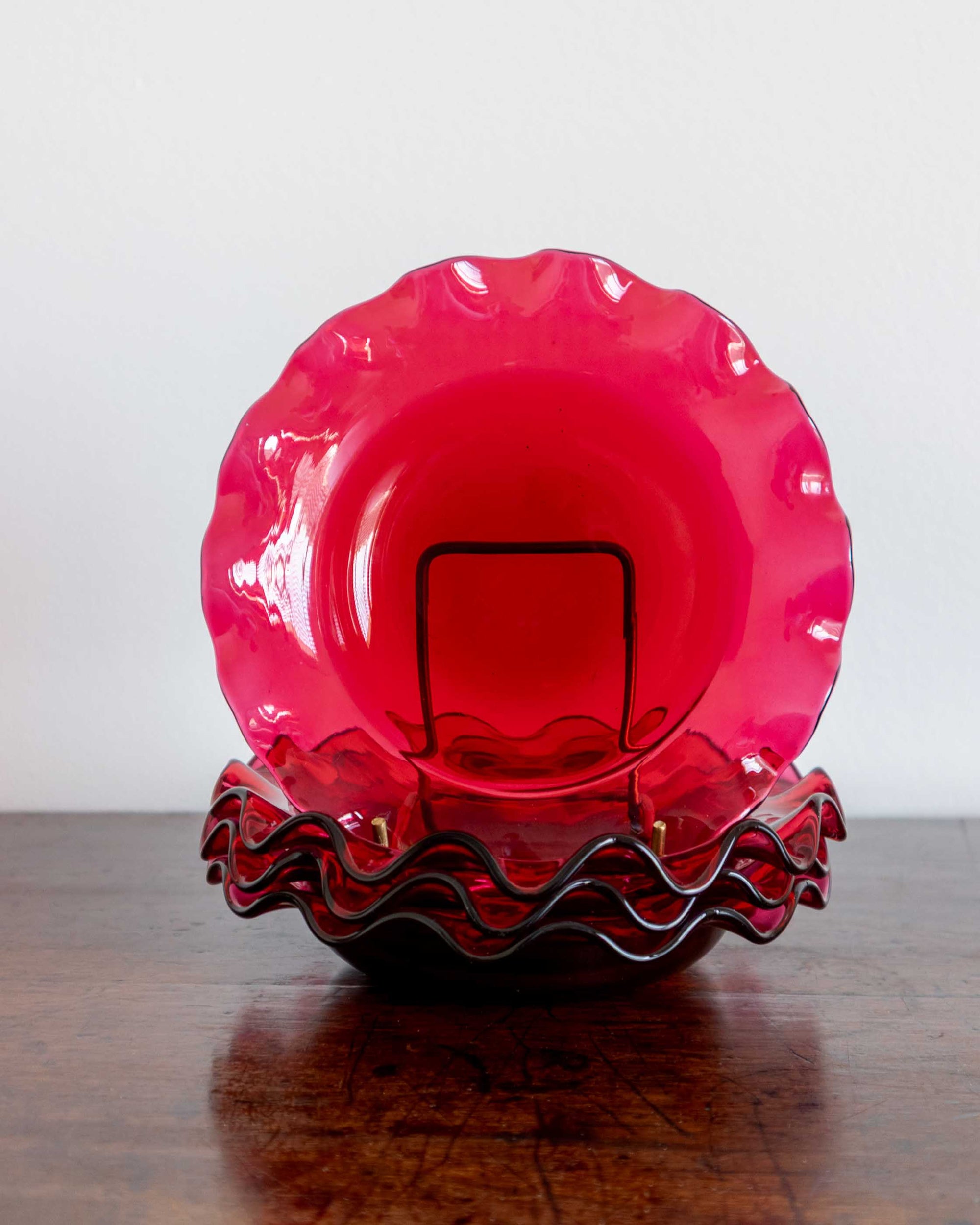 Pink glass bowl with wavy rim on a wooden surface