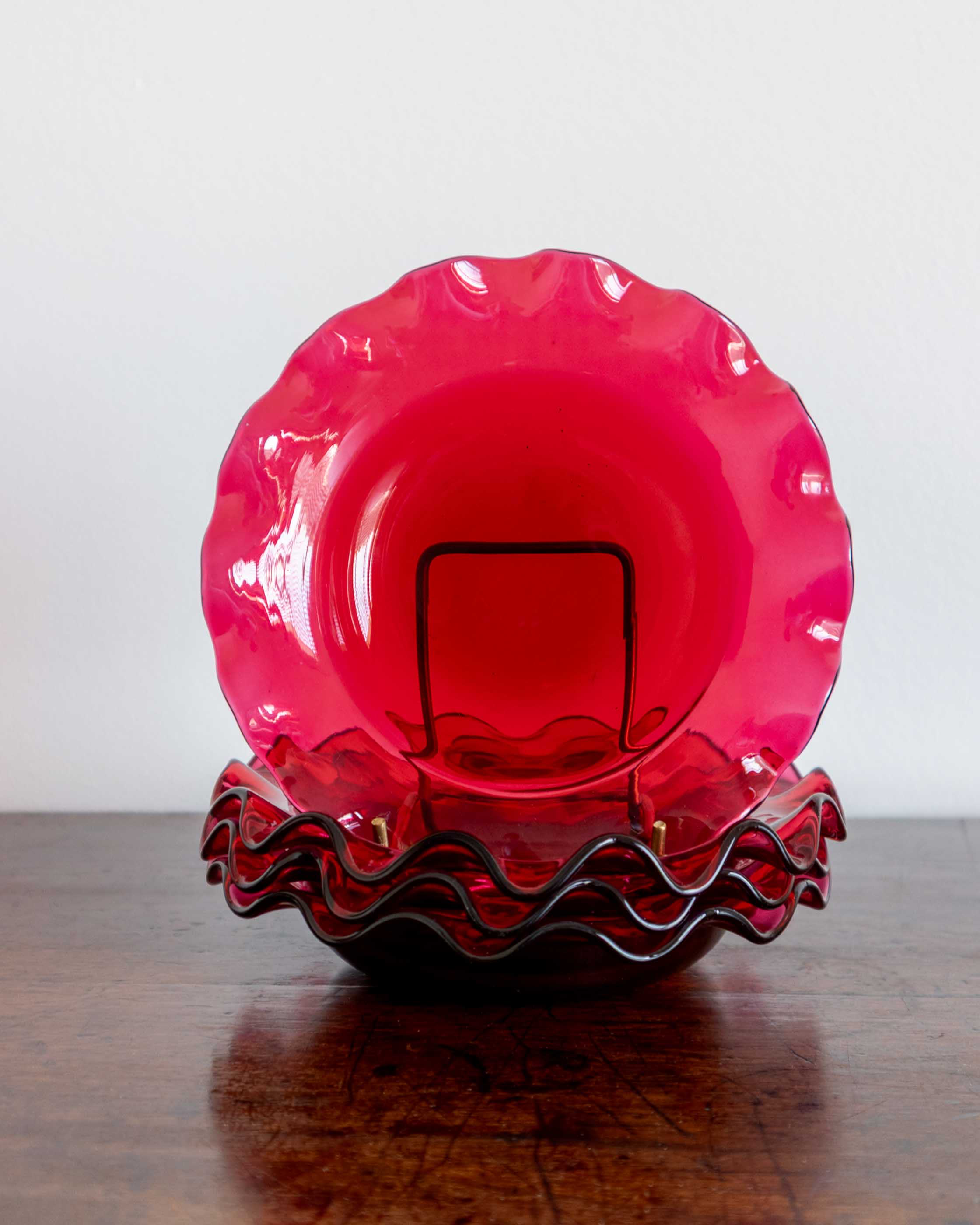 Pink glass bowl with wavy rim on a wooden surface