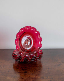 Red glass bowl with wavy edge on a wooden surface