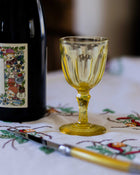 Yellow glass and bottle on a embroidered tablecloth