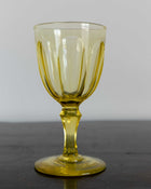 Yellow glass goblet on a dark surface with a gray background