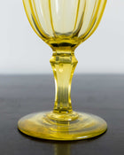 Yellow glass goblet on a dark surface with a light gray background