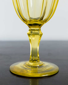 Yellow glass goblet on a dark surface with a light gray background