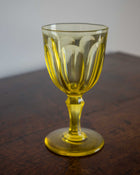 Yellow glass goblet on a wooden surface with a plain background