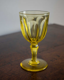 Yellow glass goblet on a wooden surface with a plain background