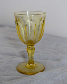 Yellow glass goblet on a grey cloth background
