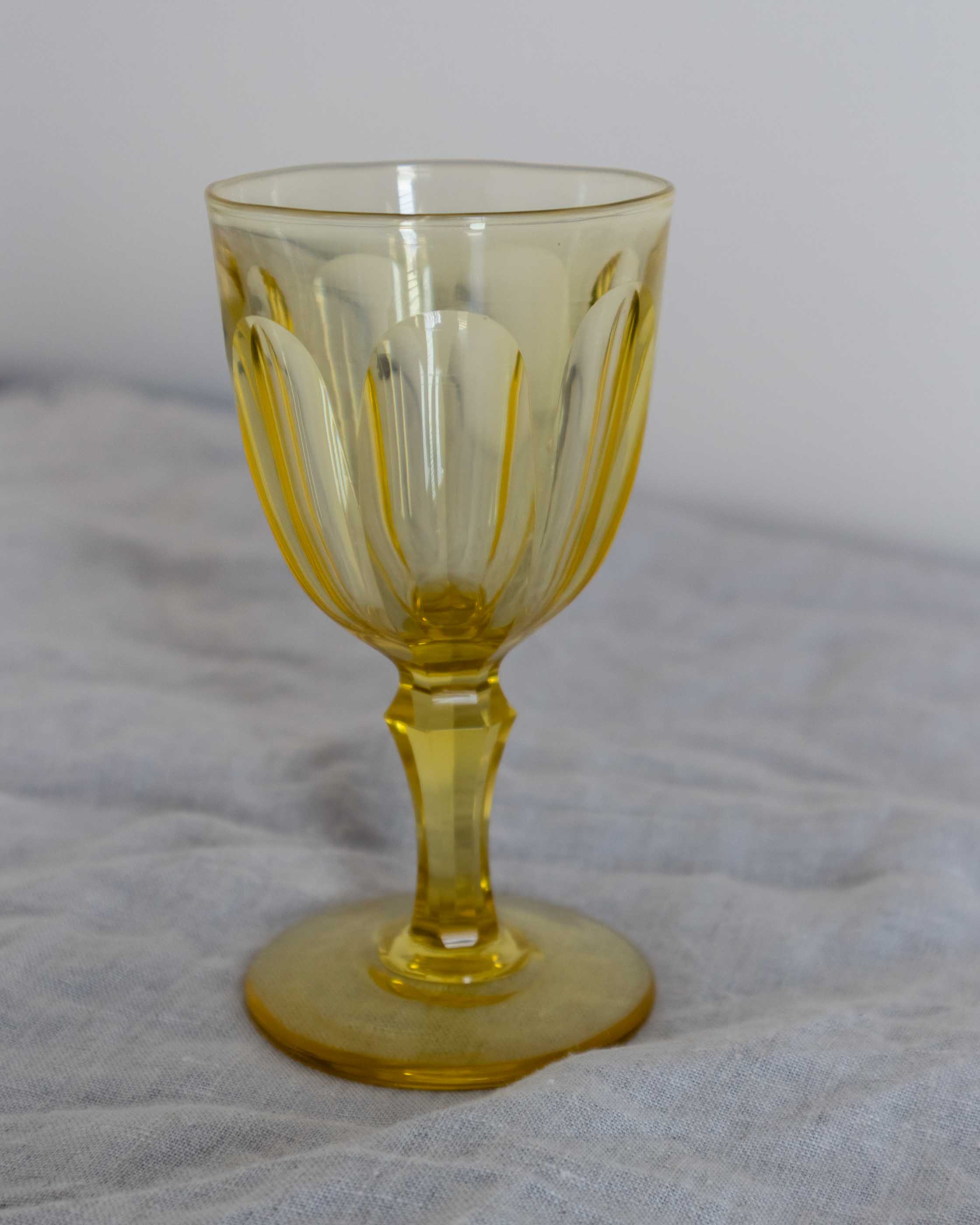 Yellow glass goblet on a grey cloth background