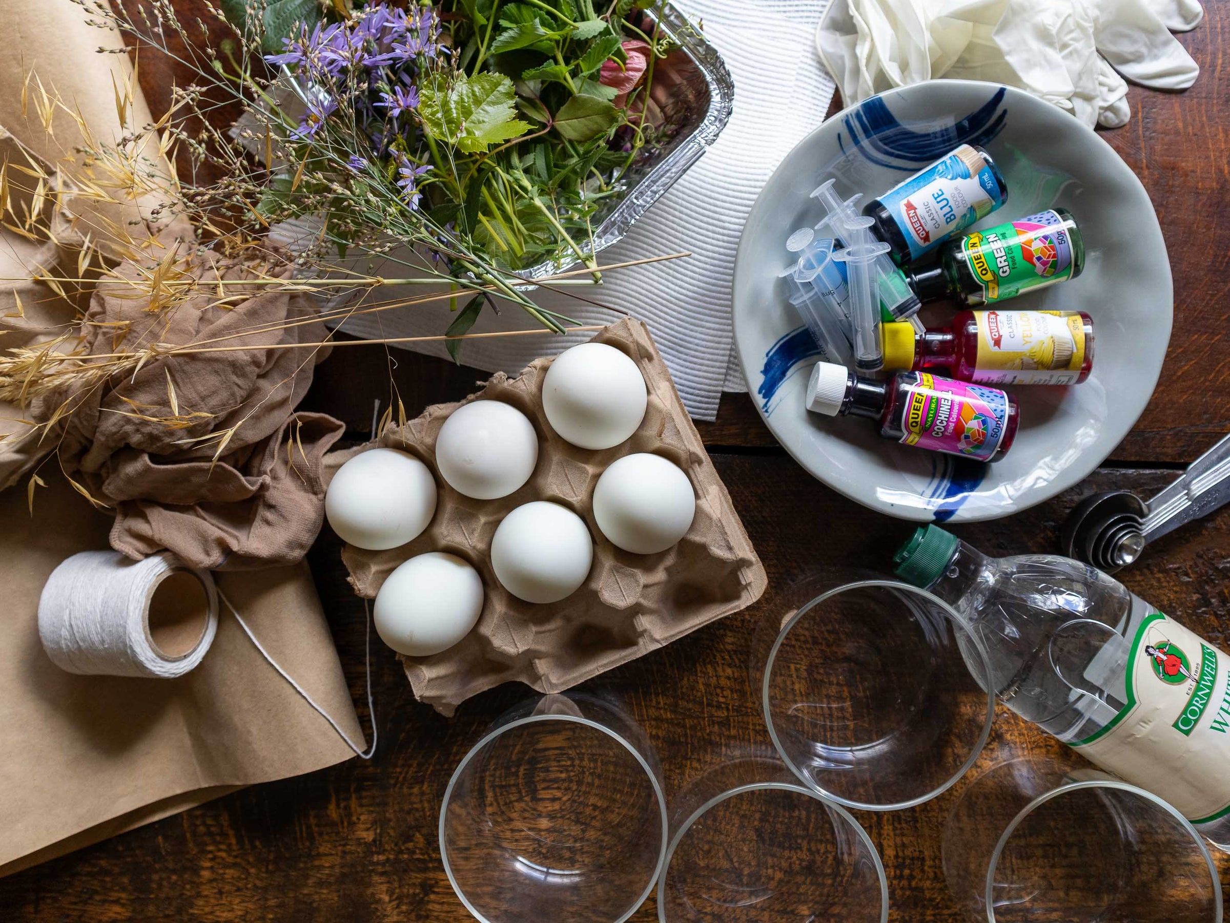 Tabletop scene with eggs, bottles, and flowers on a wooden surface
