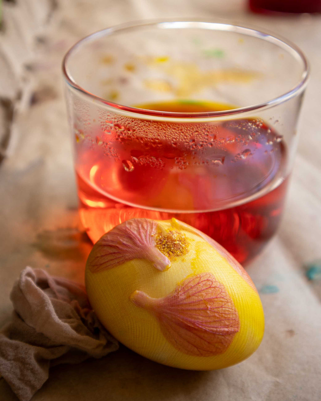 Glass of red liquid with a yellow egg on a textured surface