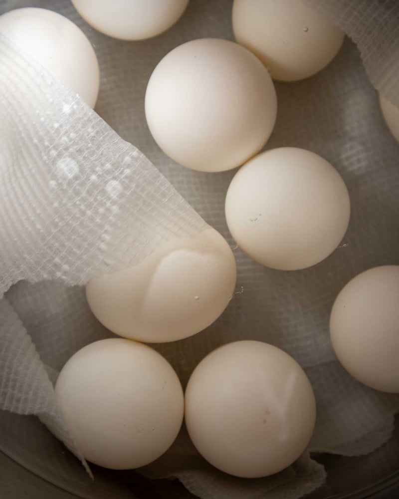 White eggs in a pot with a paper towel cover.