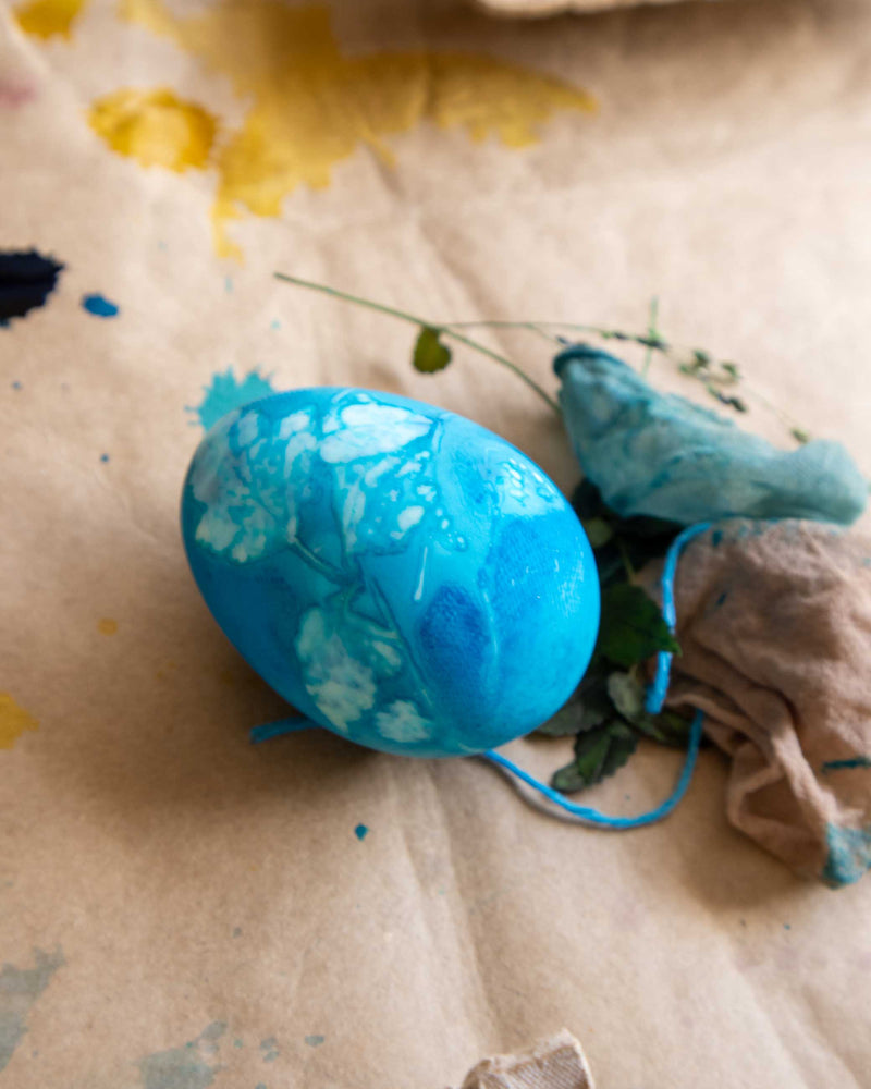 Blue egg with floral design on a textured surface