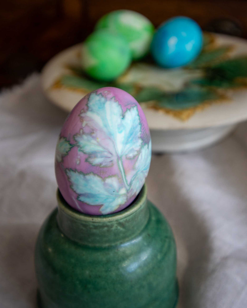 Decorative egg with floral pattern on a green bottle against a blurred background