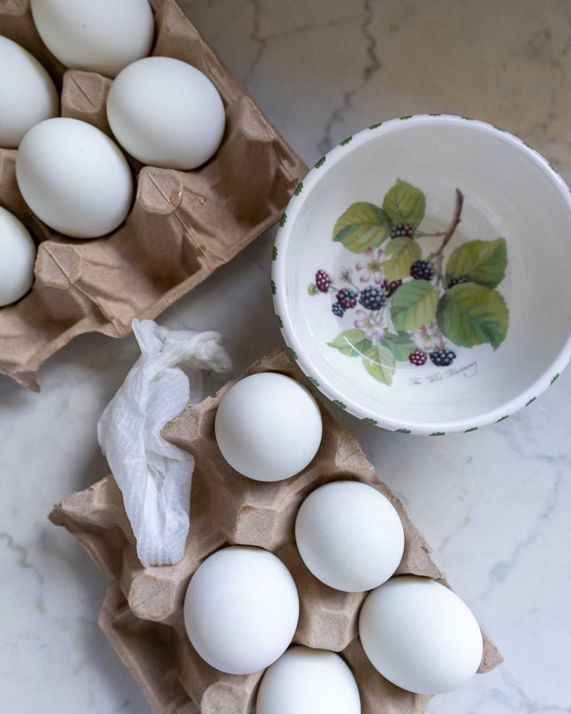 Two cartons of white eggs on a marble surface with a decorative bowl.