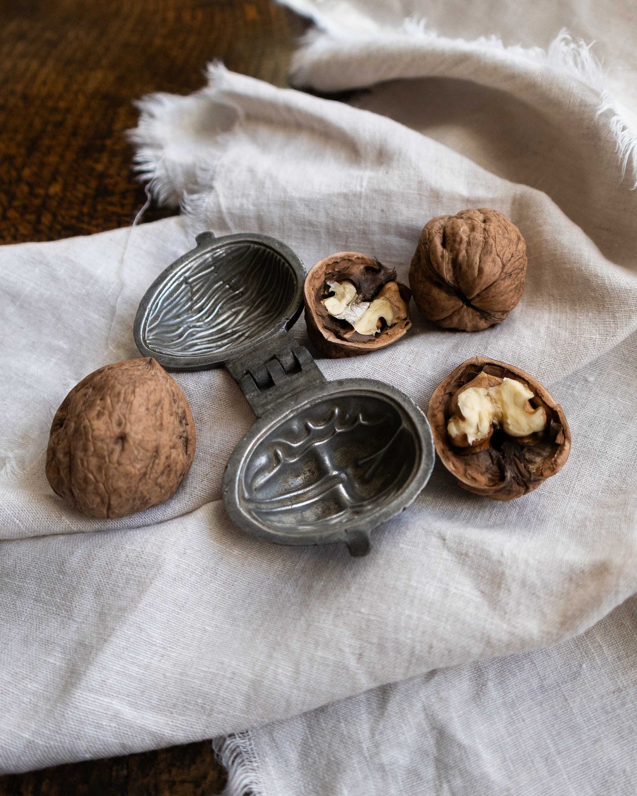 Walnut pewter ice cream mould on on a white cloth surrounded by walnuts
