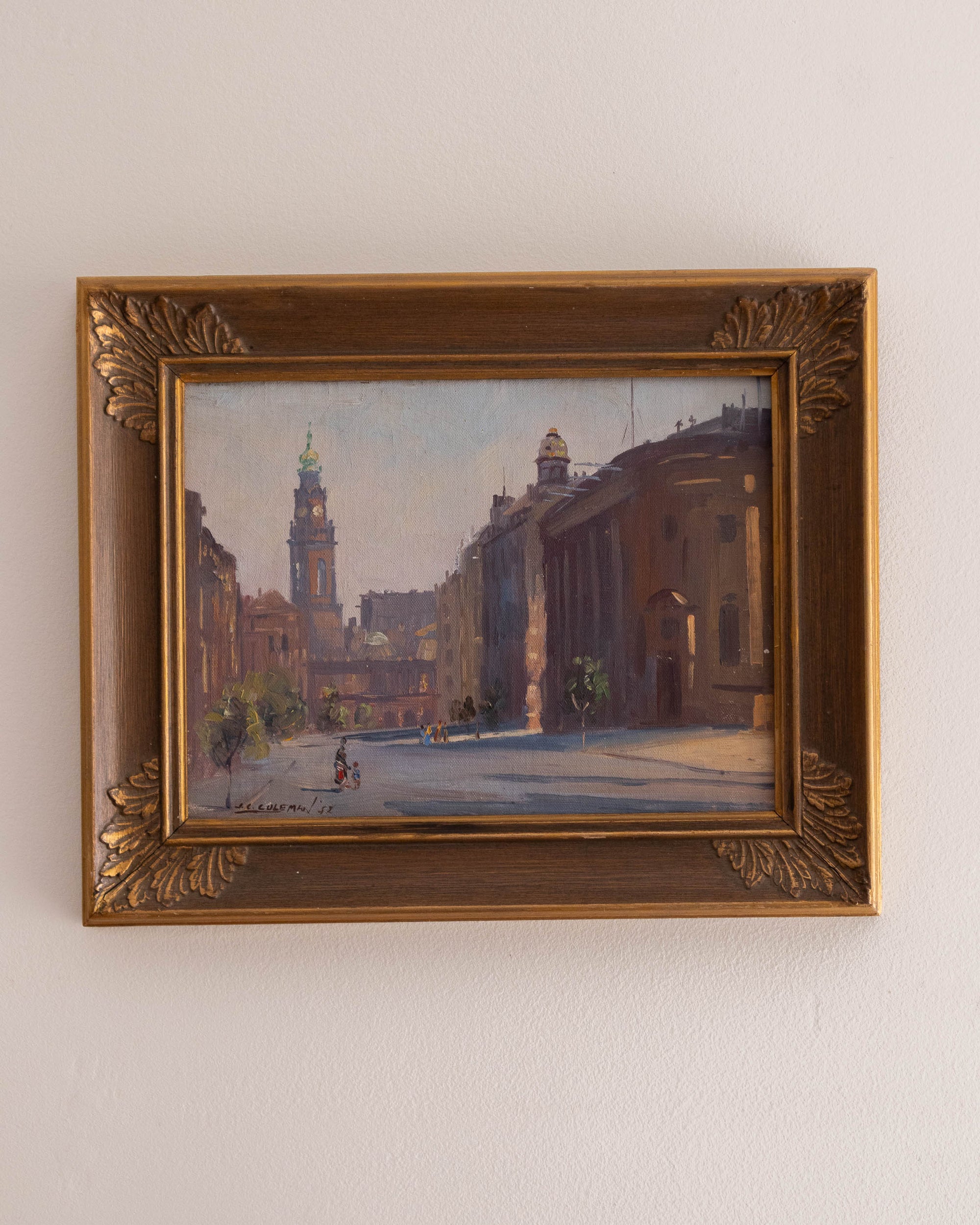 Framed painting of a city street scene on a white wall