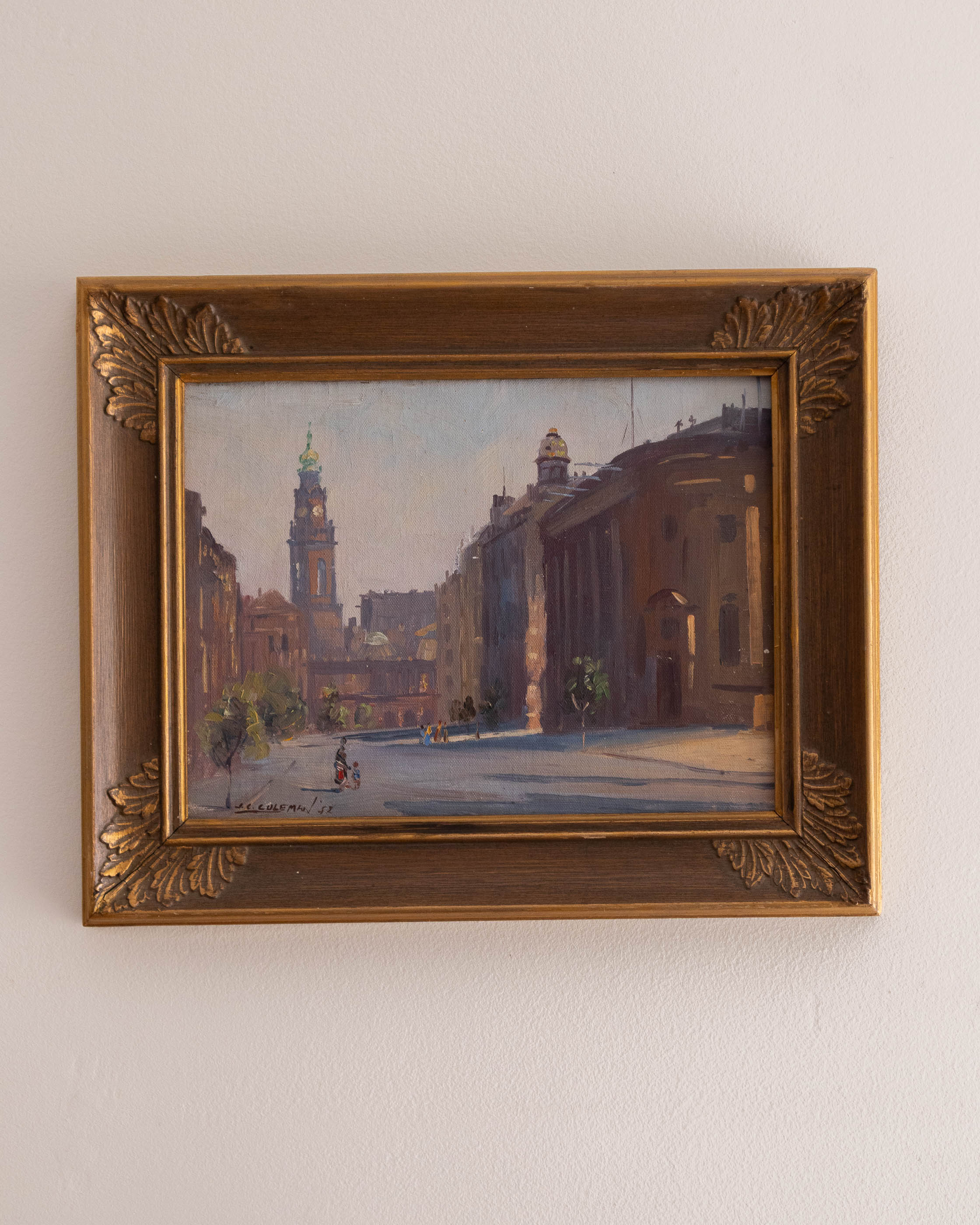 Framed painting of a city street scene on a white wall