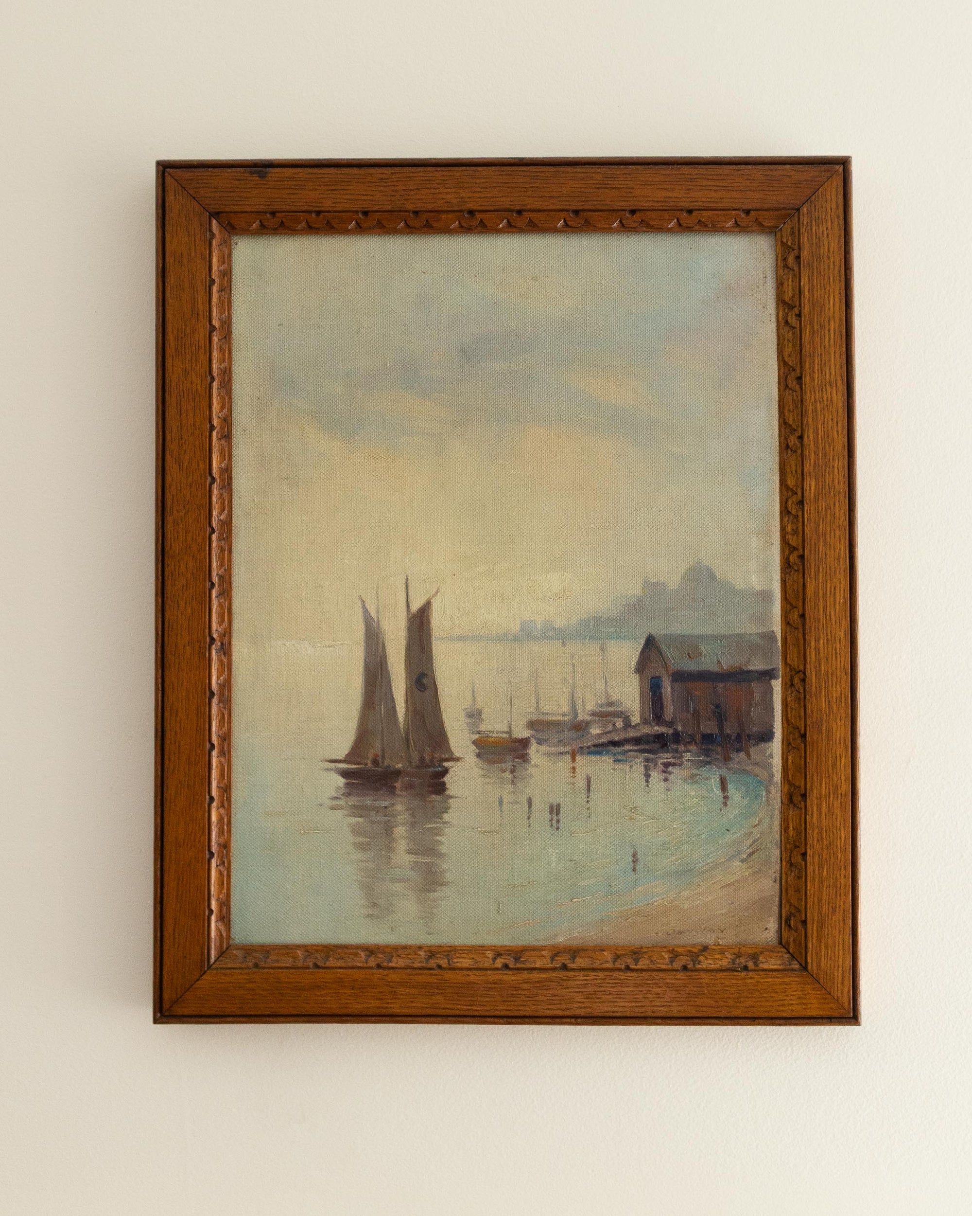 Framed painting of a harbor scene with sailboats and a wooden building.