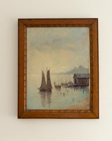 Framed painting of a harbor scene with sailboats and a wooden building.