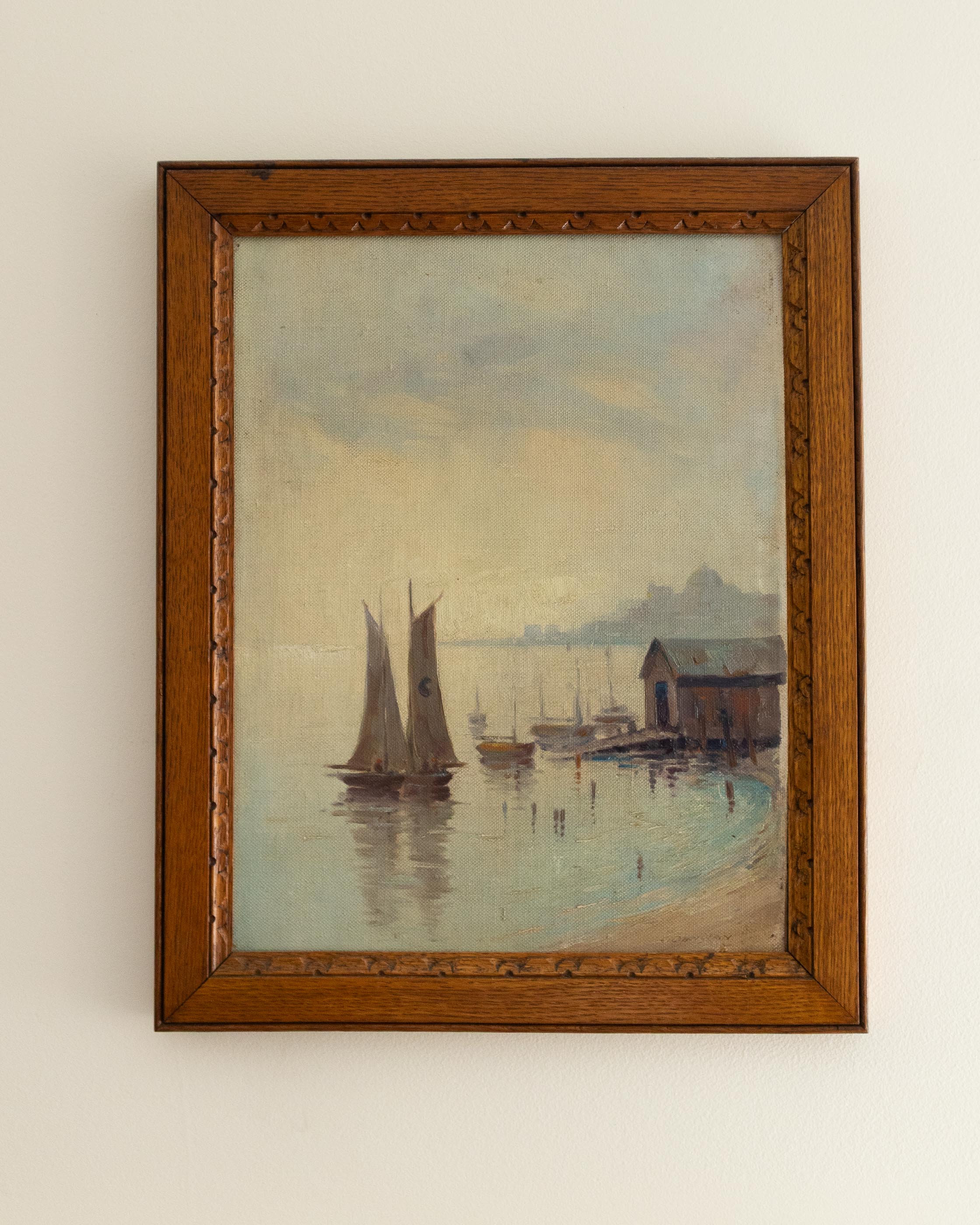 Framed painting of a harbor scene with sailboats and a wooden building.