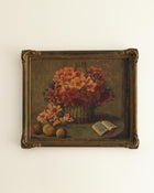 Framed still life painting with flowers and a book on a white wall