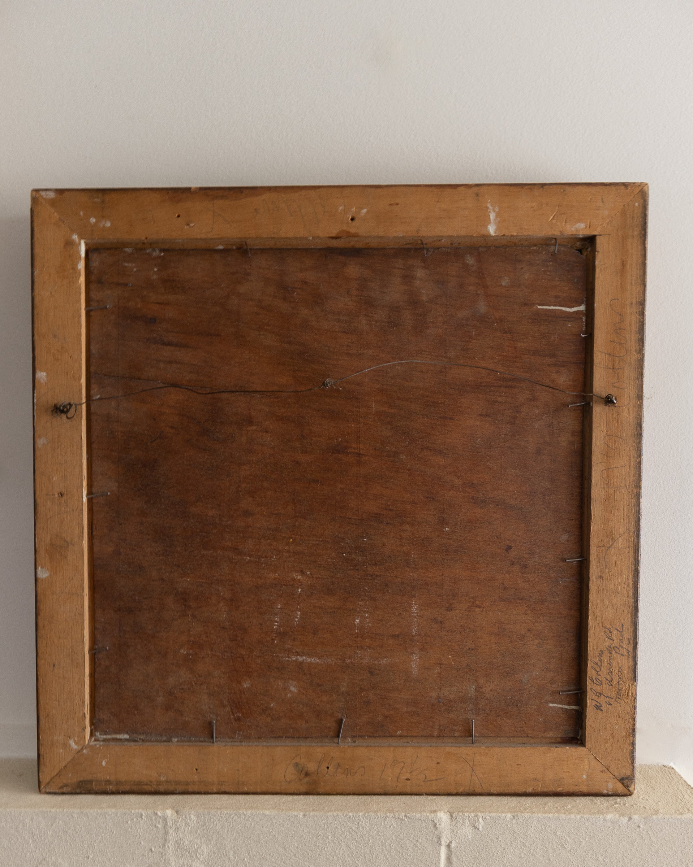Back view of a wooden picture frame on a light gray surface with a neutral background
