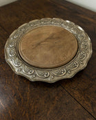 Decorative metal breadboard with engraved design on a wooden surface