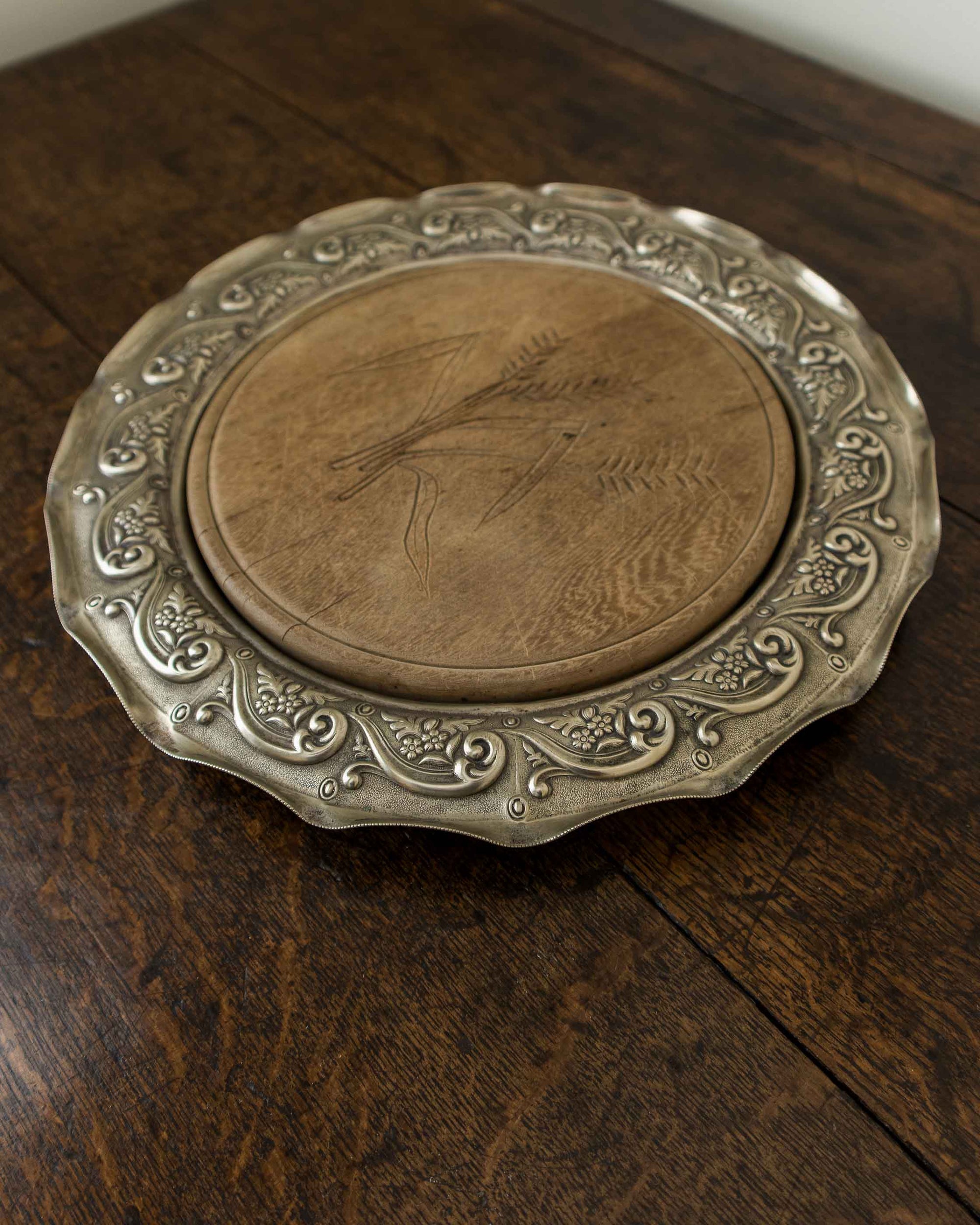 Decorative metal breadboard with engraved design on a wooden surface