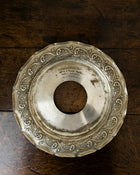 Decorative silver plate with intricate designs on a wooden surface