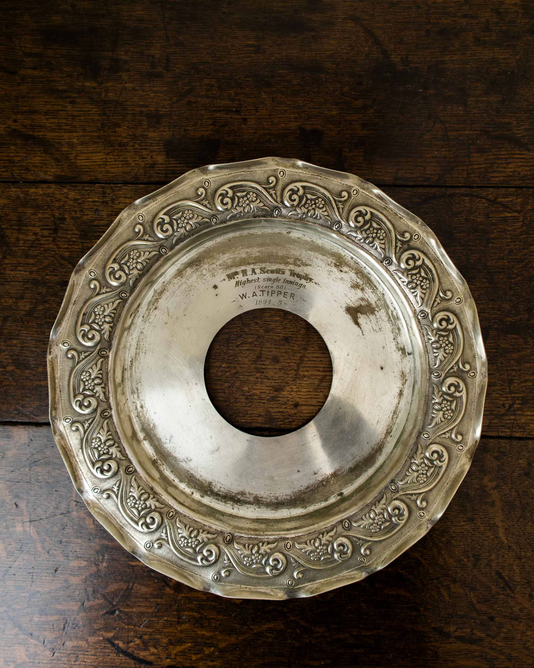 Decorative silver plate with intricate designs on a wooden surface