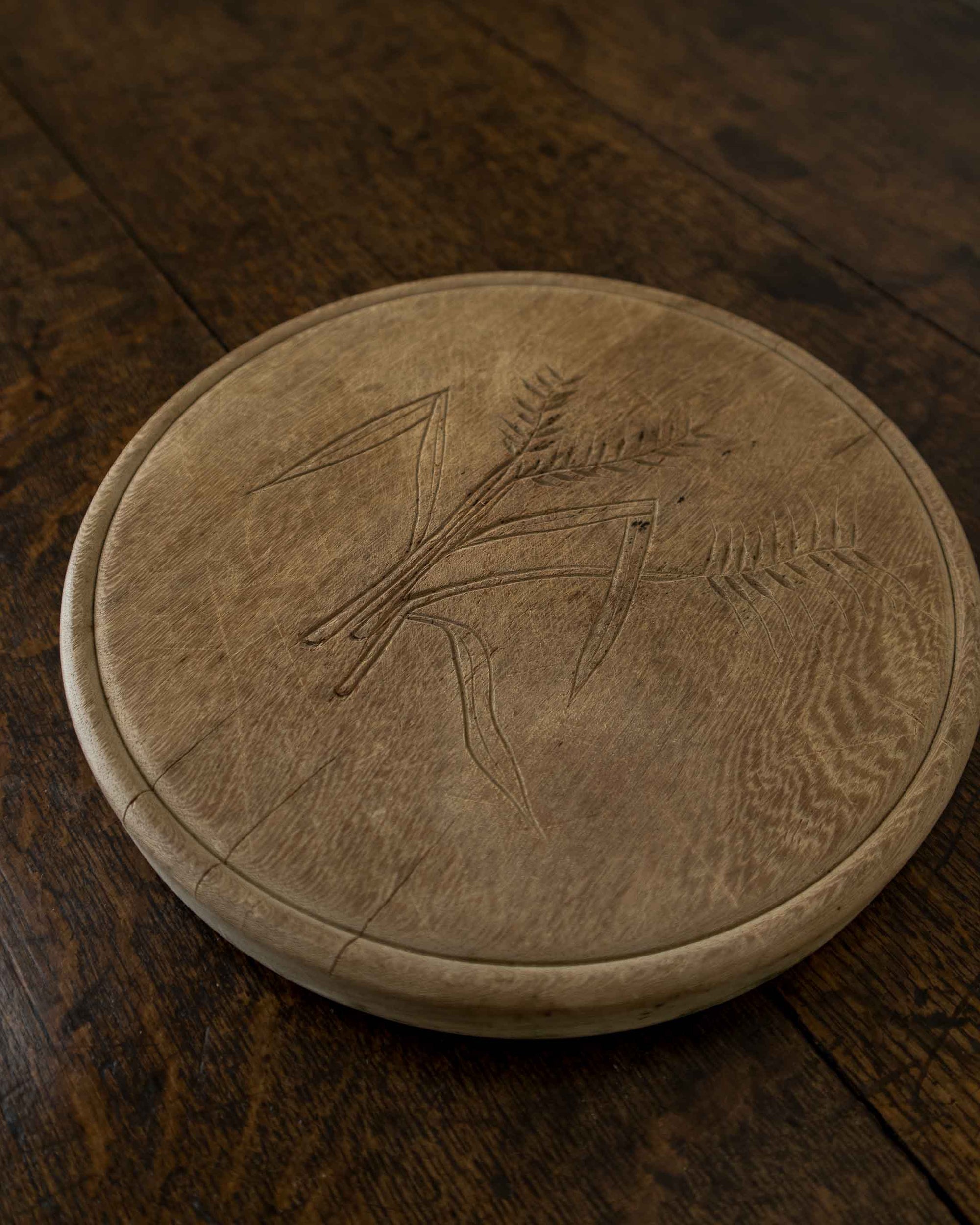 Round breadboard with engraved design on a wooden floor