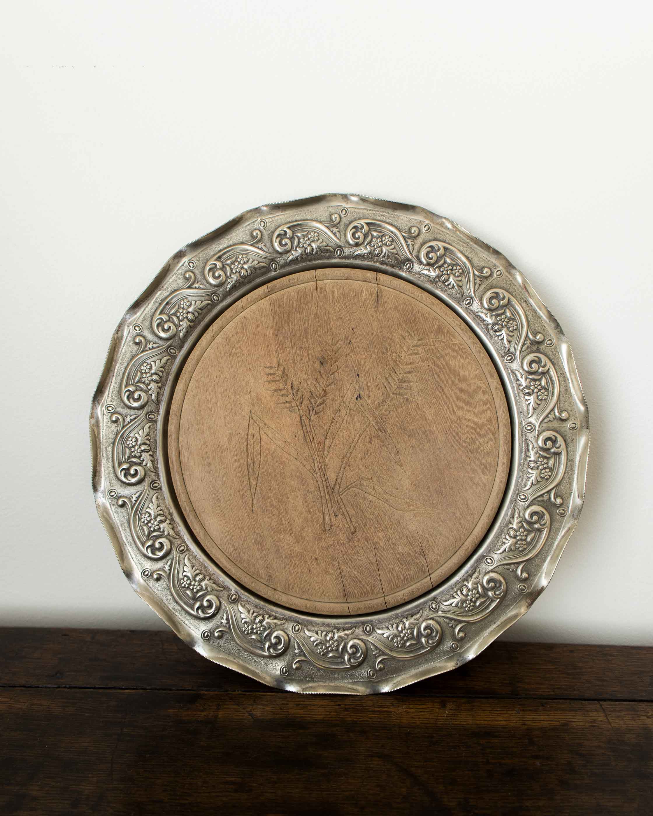 Decorative silver platter with intricate designs on a wooden surface.
