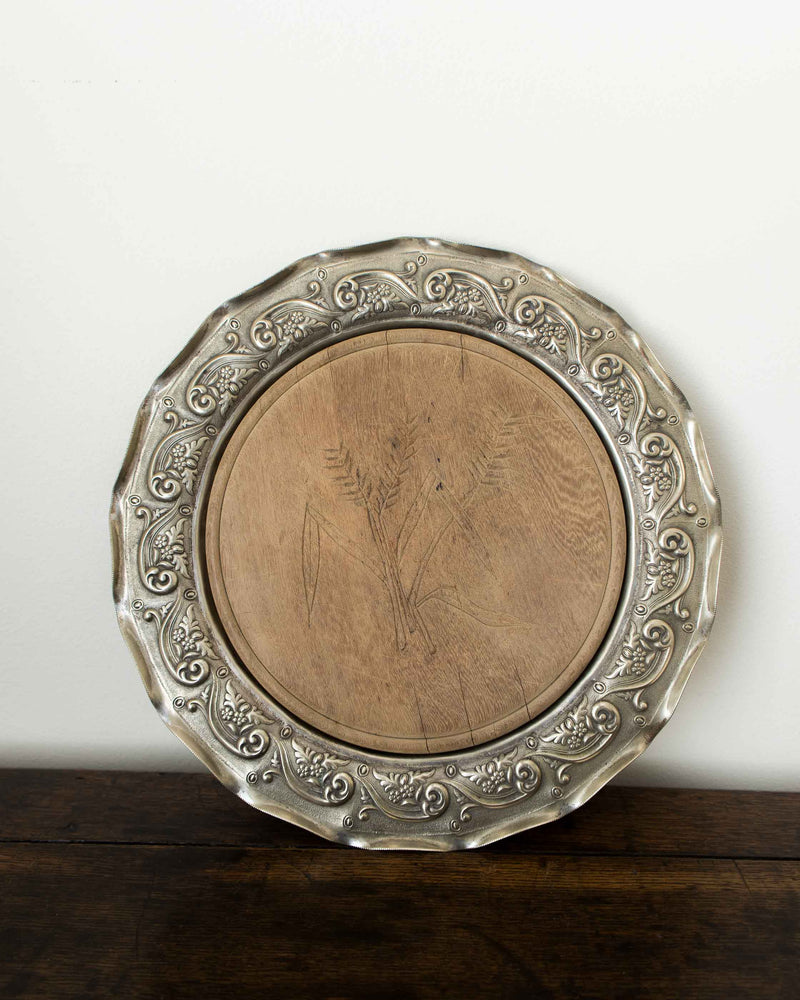 Decorative silver platter with intricate designs on a wooden surface.