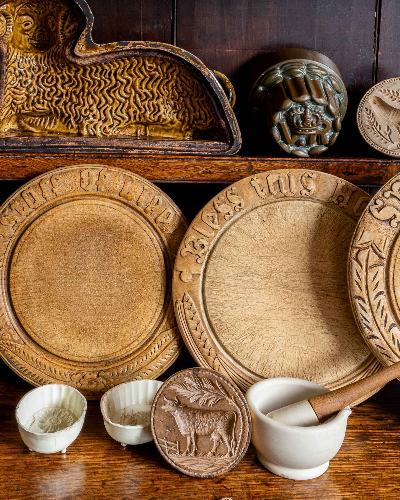 Collection of wooden breadboards and decorative moulds on a wooden shelf