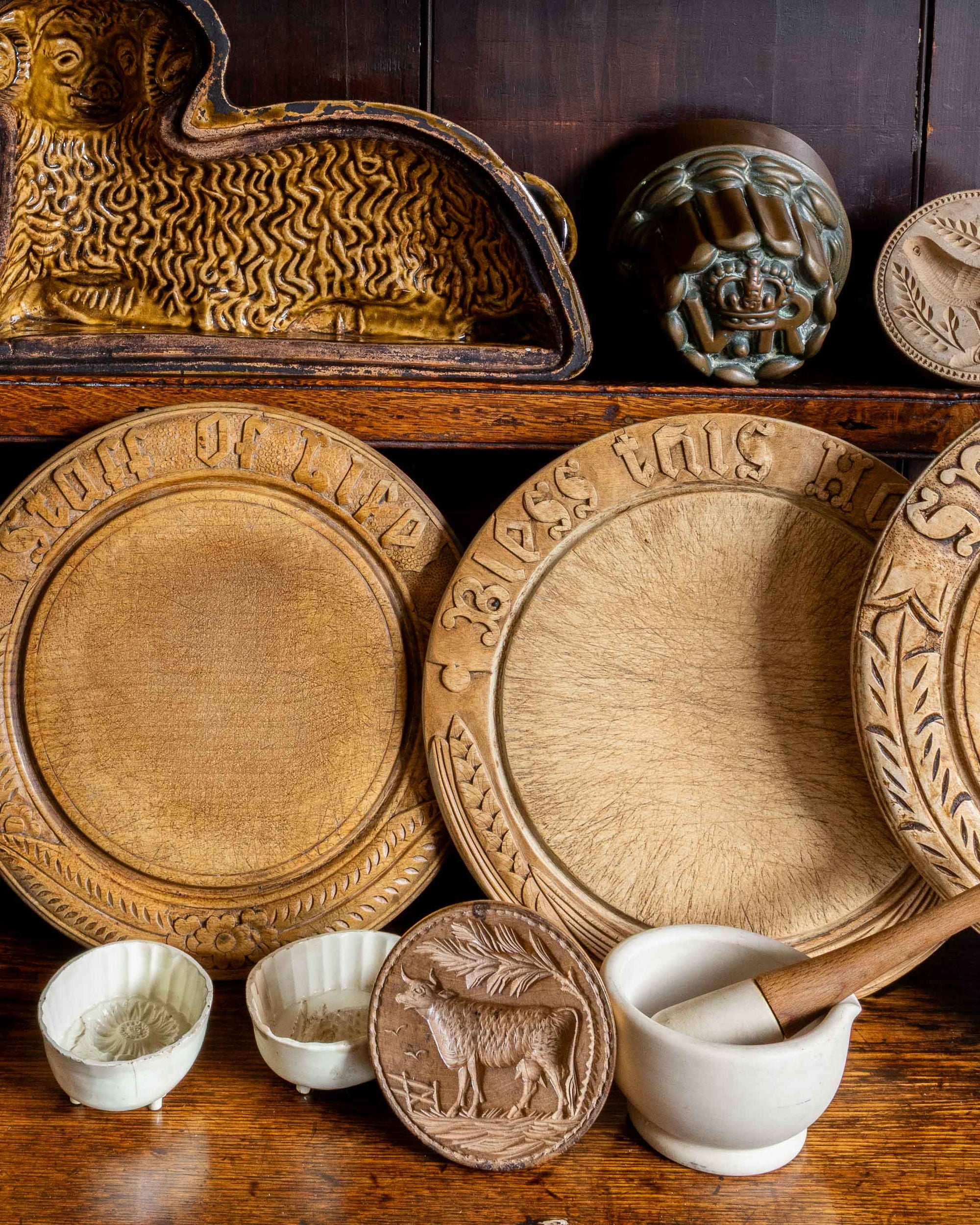 Collection of wooden breadboards and decorative moulds on a wooden shelf