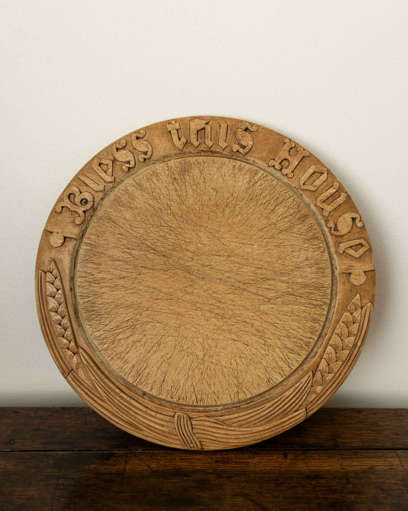 Wooden breadboard with carved text on a wooden surface